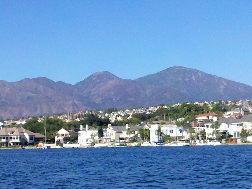 White lakefront homes along the shore of Lake Mission Viejo beneath the Saddleback range