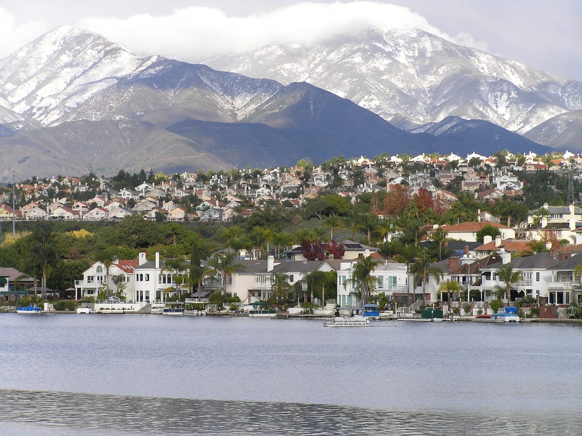 Snow-dusted Saddleback Mountain rising behind lakefront homes in Mission Viejo